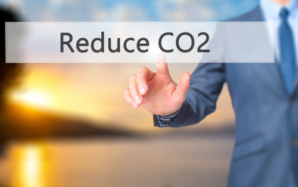 Person in a suit touching a sign that says Reduce CO2.