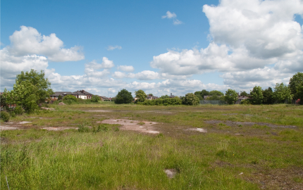 Empty lot with houses in the distance