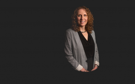 Michele L Cohen is smiling, wearing a grey jacket, and a black shirt.