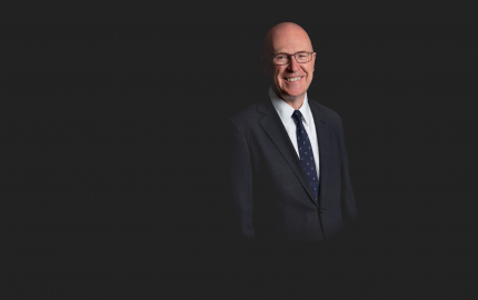 Stephen J. Cullen is smiling, wearing a dark suit, white shirt, and a blue tie.
