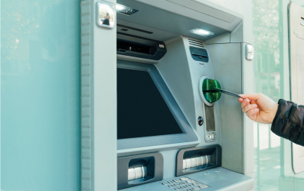 Using a card to withdraw money from their ATM