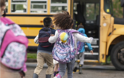 Young children running to get on the school bus.