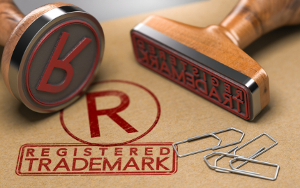 Two stamps and the stamper one saying registered trademark and one with an R with a circle around the letter and three paperclips.