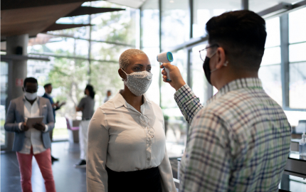 Person having their temperature taken with an infrared thermometer in an office building.