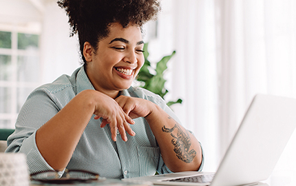 Person sitting in front of a laptop smiling.