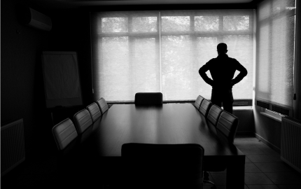 Person standing in front of a shaded window in a boardroom.