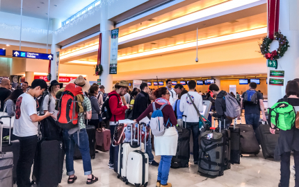 Crowd of passengers waiting on a departure line at an airport.
