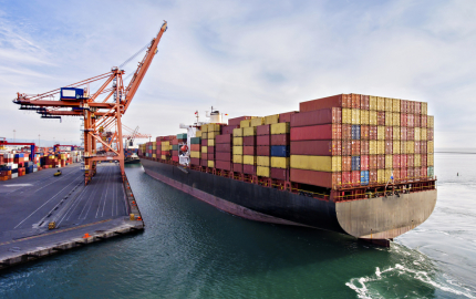 Cargo ship maneuvering at dock with a ship full of cargo.