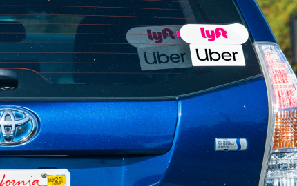 Back window of a vehicle with Lyft and Uber stickers