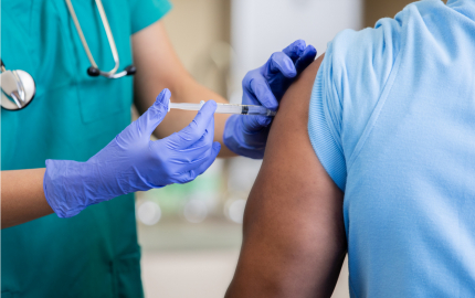 Medical professional giving a person a shot in the upper arm.