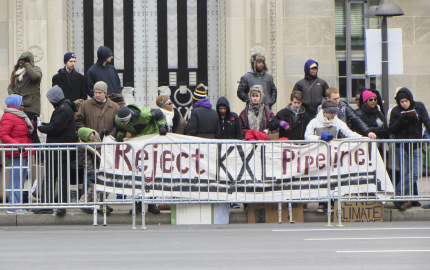 Protesters in Montana behind barricades holding a sign that reads Reject KXL Pipeline.