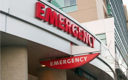 Outside of hospital emergency room showing emergency signs.