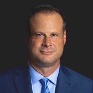 Andrew M. Weiner is smiling, wearing a blue suit, blue shirt, and blue tie with darker blue dots. Close up on face.