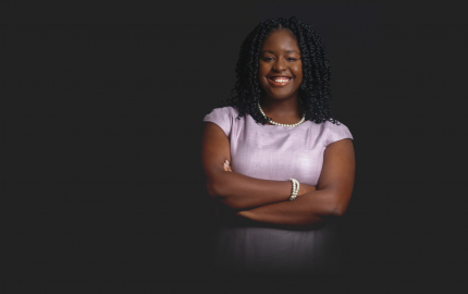 Brianna D. Gaddy is smiling and wearing a lavender dress.