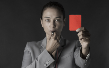 a person blowing a whistle and hold up a red card.