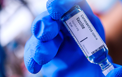 A gloved hand holding a vile of Coronavirus vaccine.