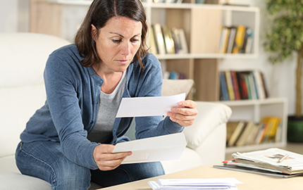 Person sitting on a couch looking at a piece of mail.