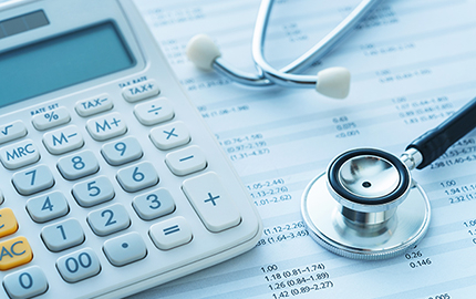 A calculator and stethoscope on top financial papers.