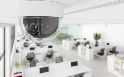 Round security camera on the ceiling overlooking an office area.