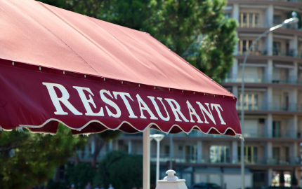 Red awning with restaurant printed on the side in white letters.