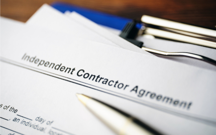 Top of an independent contractor agreement and a pen lying on top.