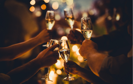 Hands holing wine glasses in a cheers gesture.